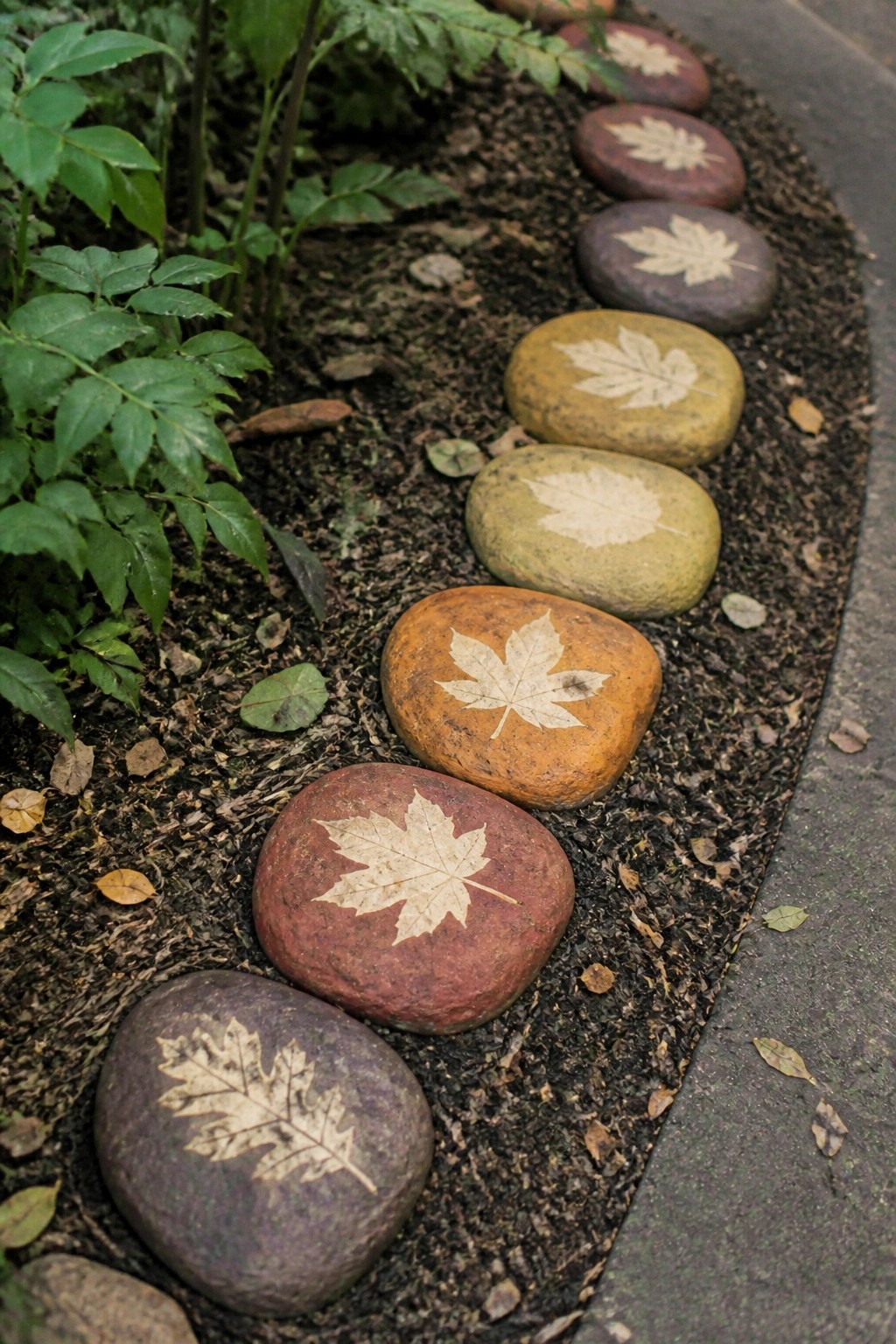Colorful stones etched with maple leaves line a winding garden path.