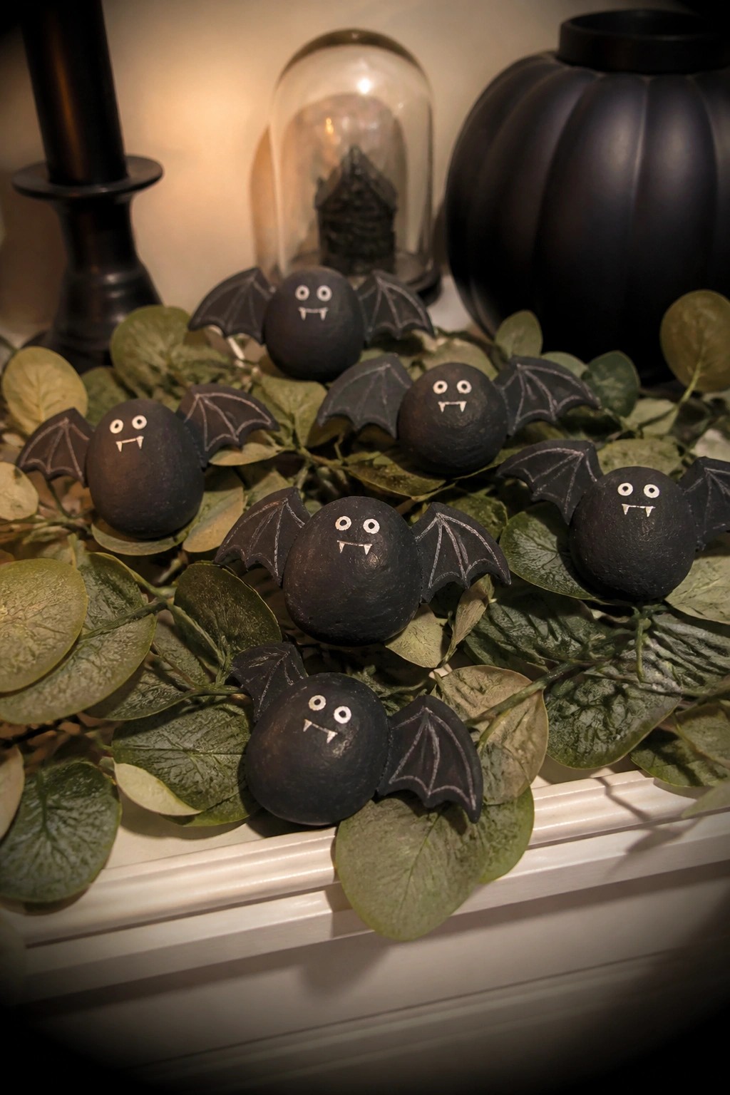 Black stone bats with wings and fangs on green leaves amid Halloween decor.