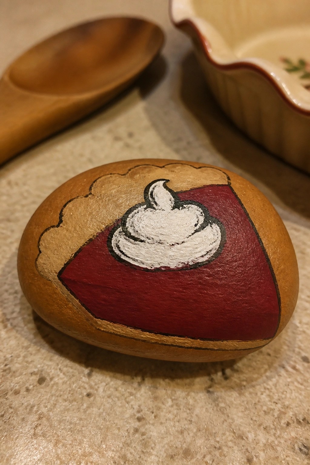 Painted rock resembling a pie slice with red filling and whipped cream topping