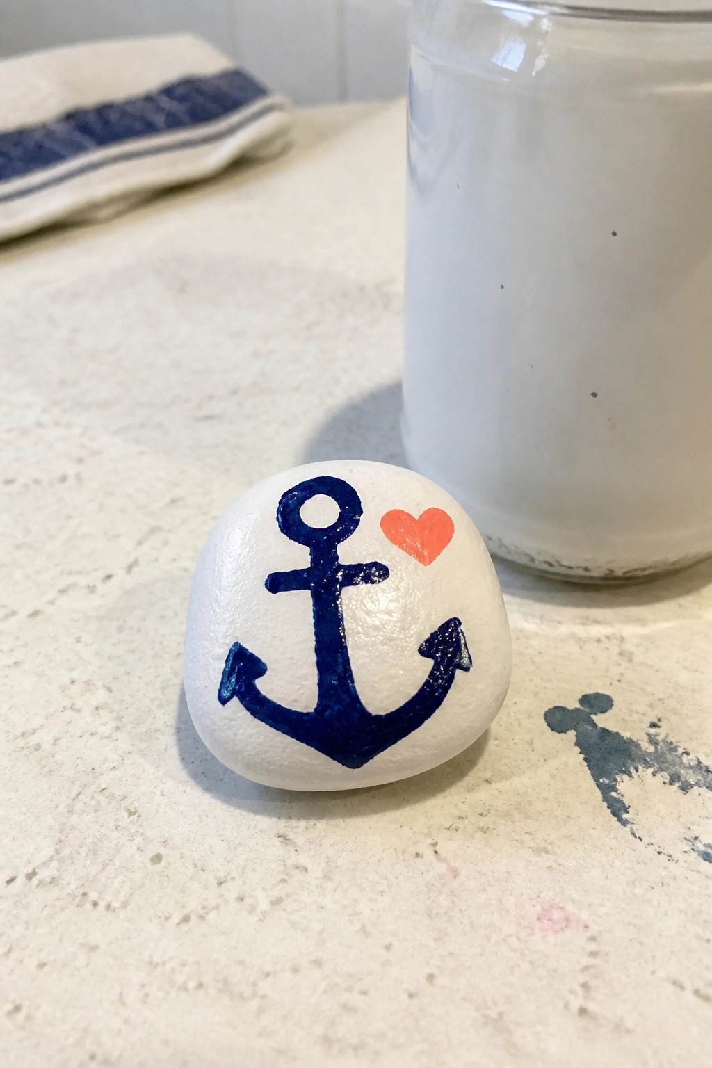 White rock painted with blue anchor and red heart on marble counter
