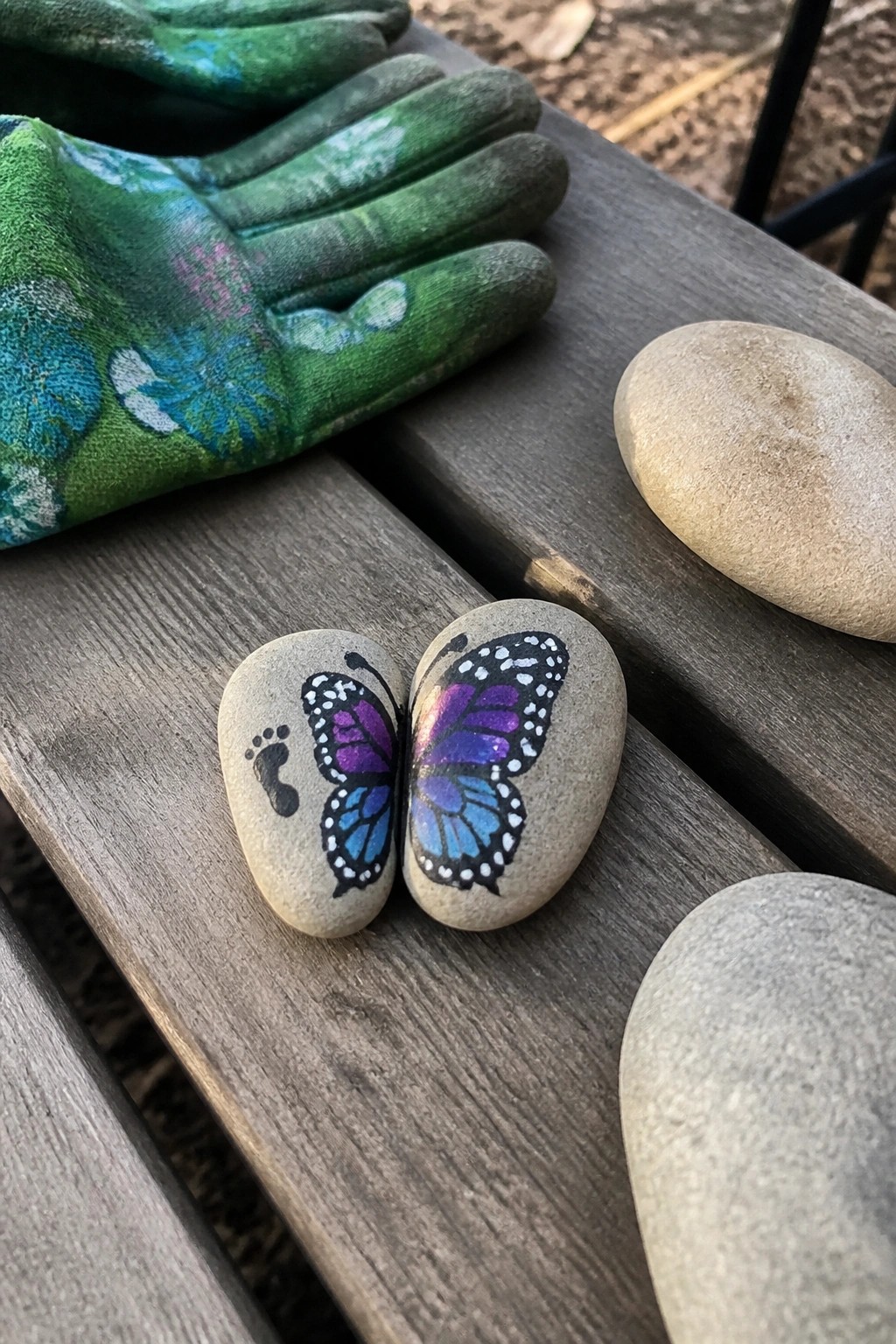 Green floral gloves beside split rocks painted as blue-purple butterfly with footprint.