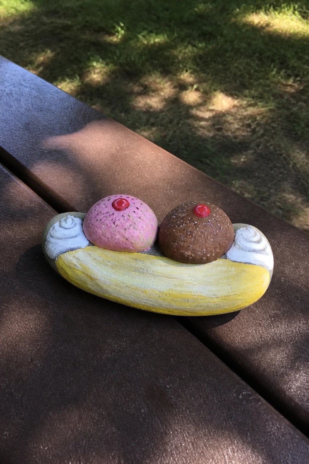 Painted rocks forming a banana split with pink and brown scoops on yellow base.