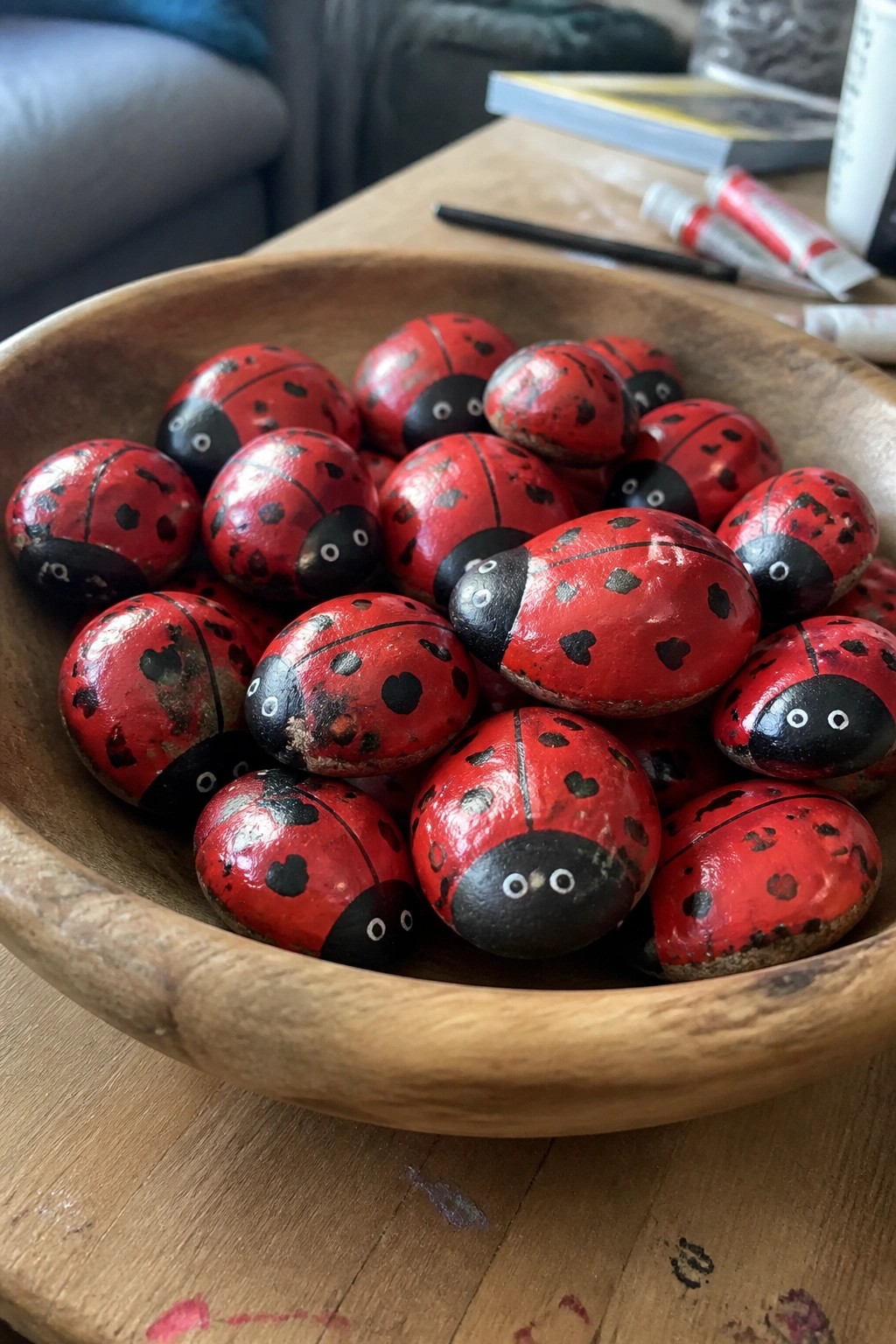 Wooden bowl filled with red and black painted ladybug rocks on table