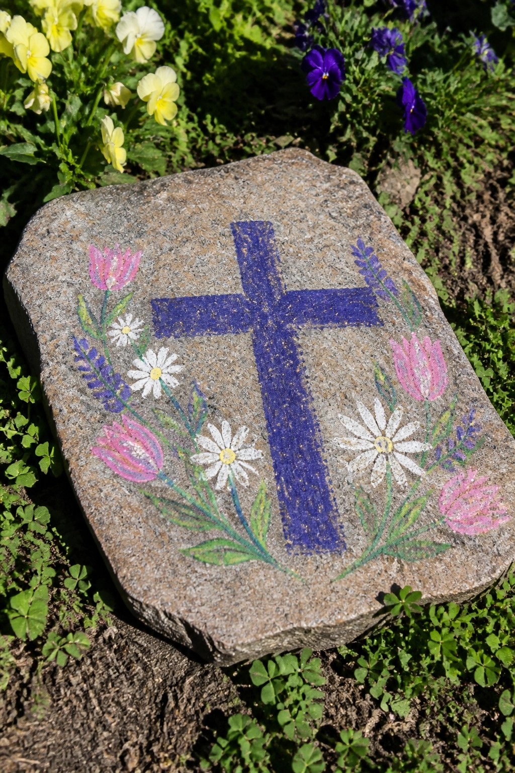 Granite stone with blue cross, pink tulips, white daisies, and lavender.