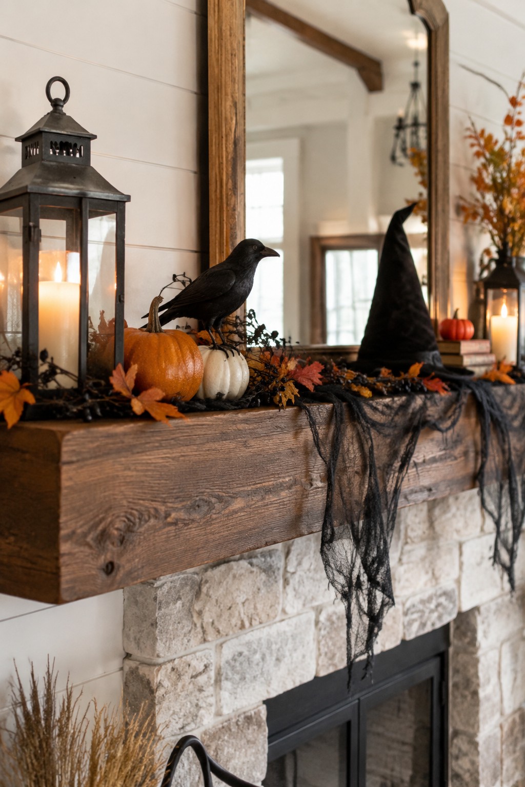 Wooden mantel decorated with a black crow on a pumpkin, a tall witch hat, orange and white pumpkins, lanterns, and black gauze draped across the edge above a stone fireplace.